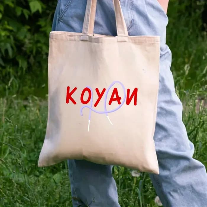 Un sac fourre-tout en toile de couleur crème avec texte Koyani et motifs