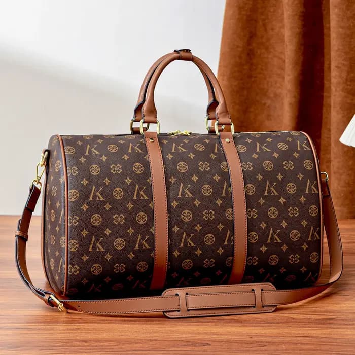 Sac de voyage marron à motif monogramme, anses supérieures, bandoulière réglable, poche avant et détails dorés