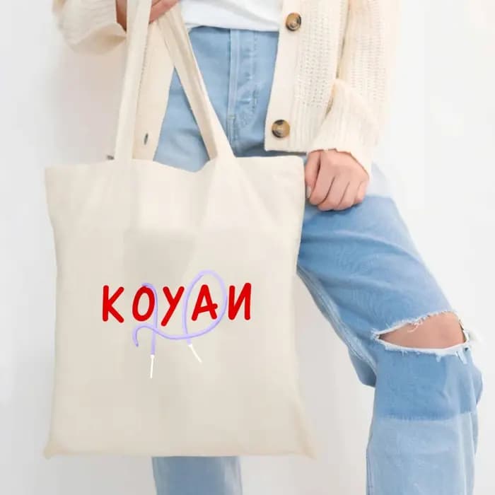 Un sac fourre-tout en toile de couleur crème avec texte Koyani et motifs