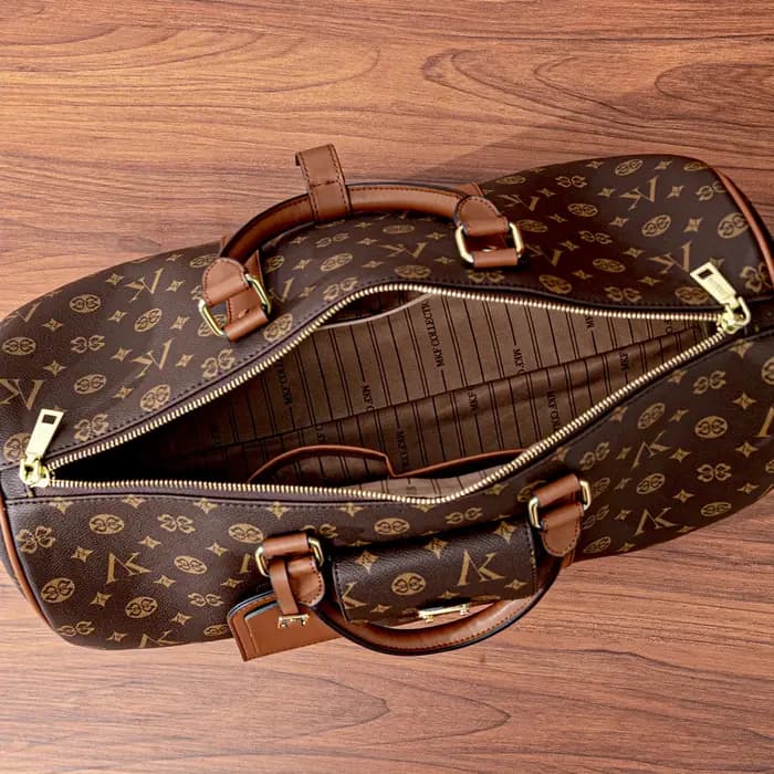 Sac de voyage marron à motif monogramme, anses supérieures, bandoulière réglable, poche avant et détails dorés