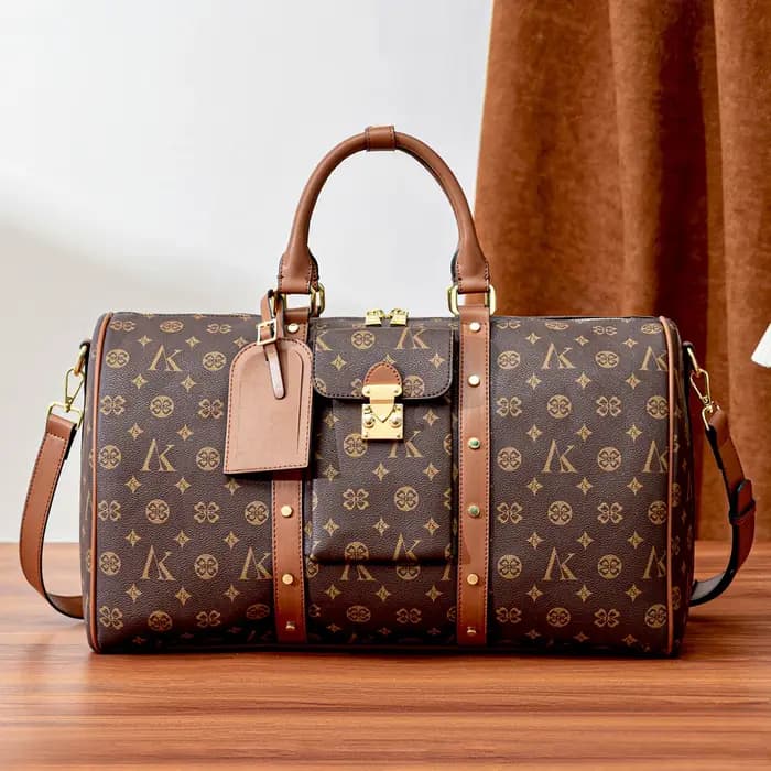 Sac de voyage marron à motif monogramme, anses supérieures, bandoulière réglable, poche avant et dét