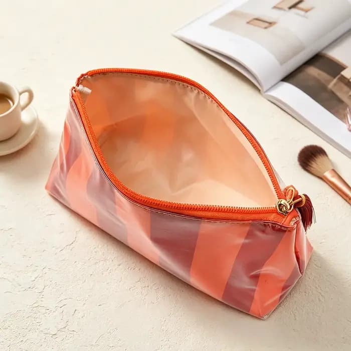 Pochette à maquillage brillante en PU avec fermeture éclair et pompon. Sac de voyage portable multi-couleurs à rayures